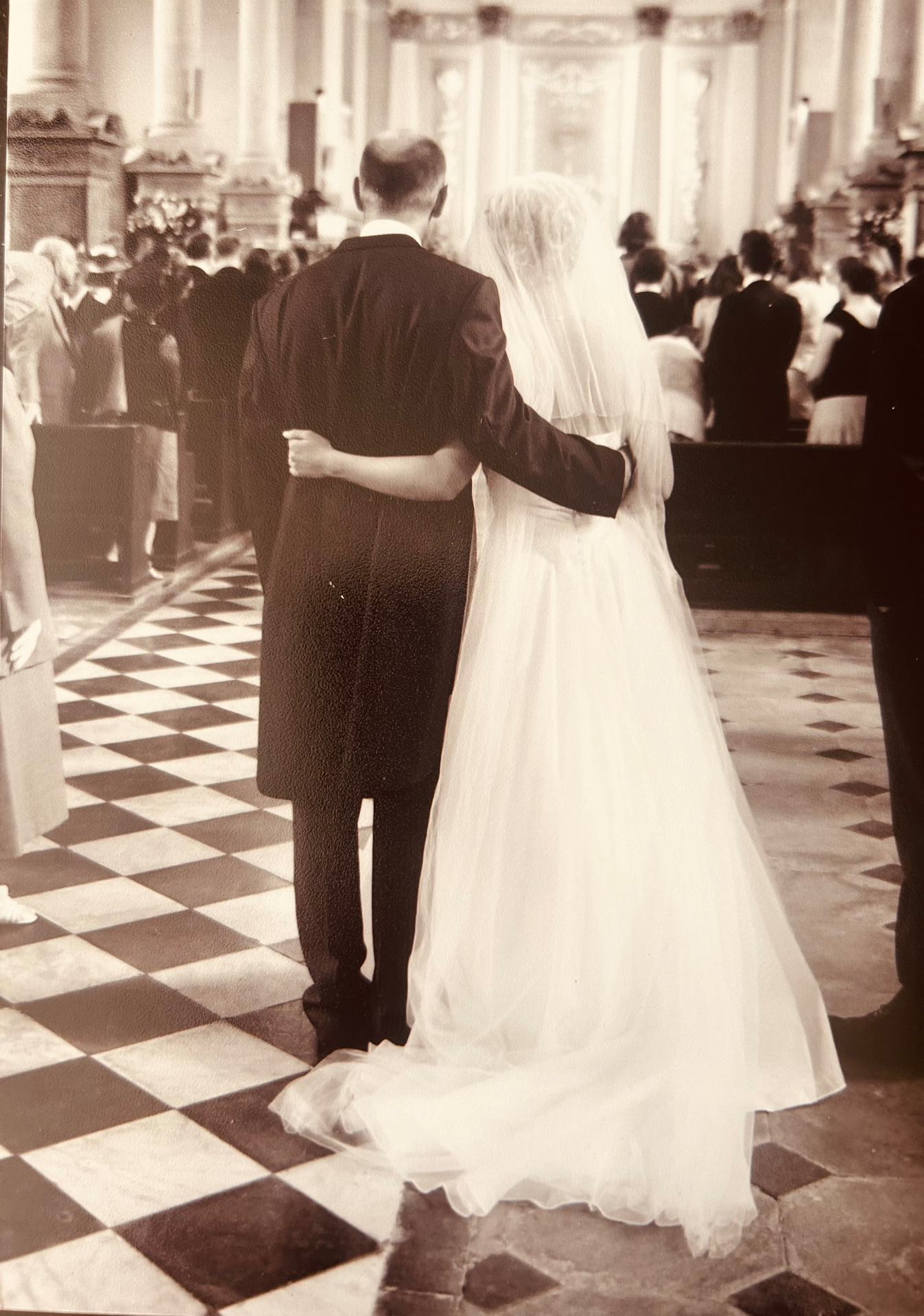 A vintage photograph of a bride and groom walking down the aisle together