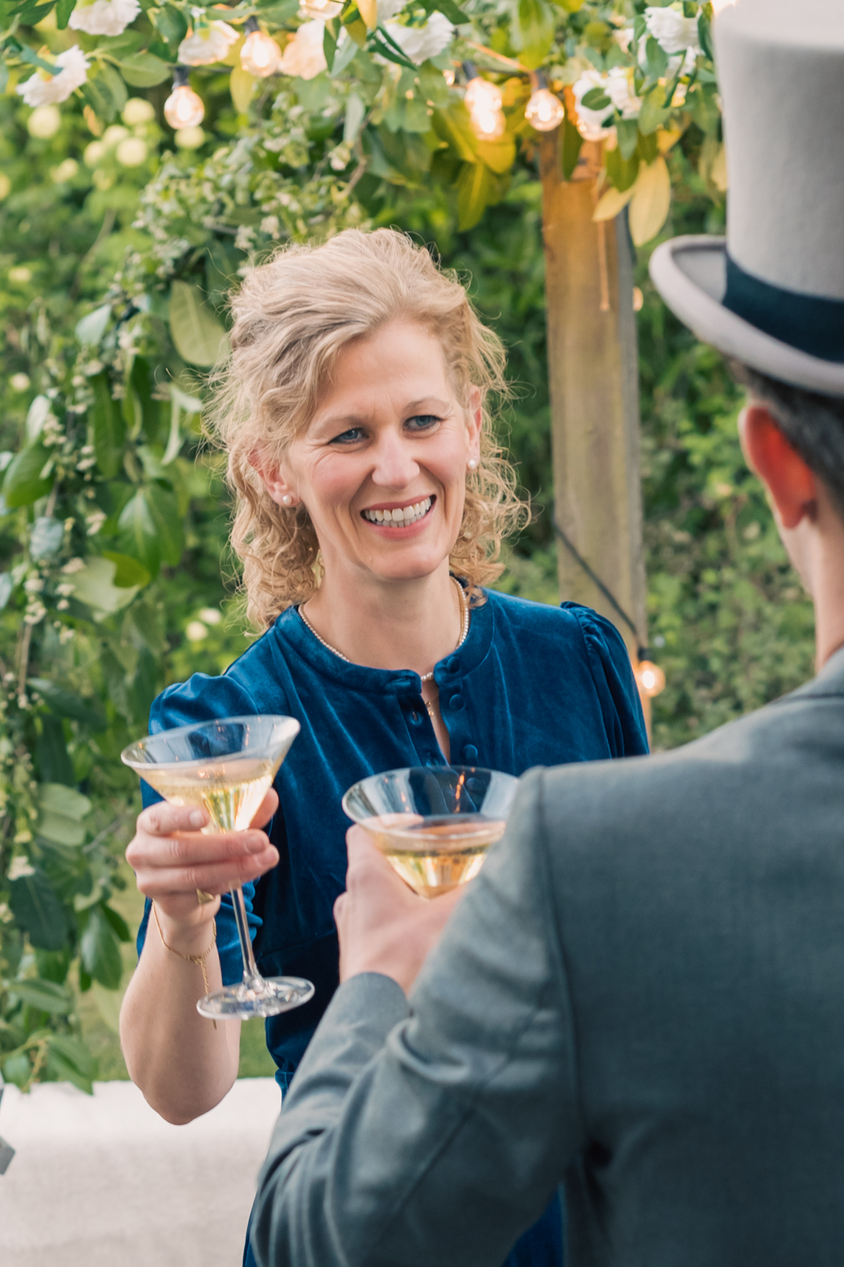 Samantha raising a coupe of champagne in a toast with a guest