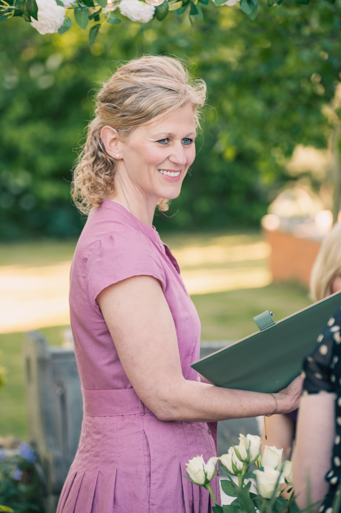 Samantha smiling while reading a ceremony script in a garden